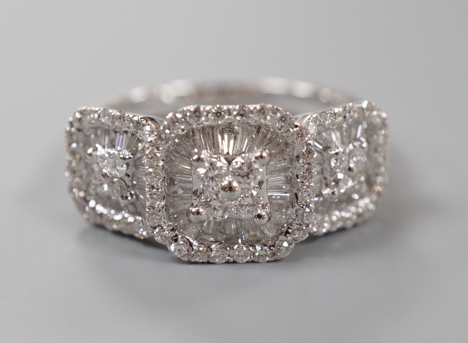 A modern 750 white metal, trapeze and round cut diamond set triple cluster dress ring, size M, gross weight 7 grams